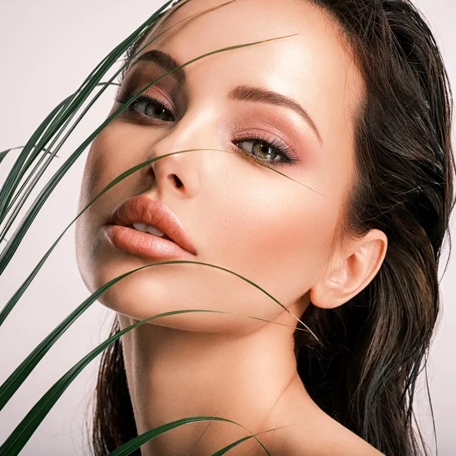 Young beautiful woman with green leaves near face and body. Skin care beauty treatments concept.
